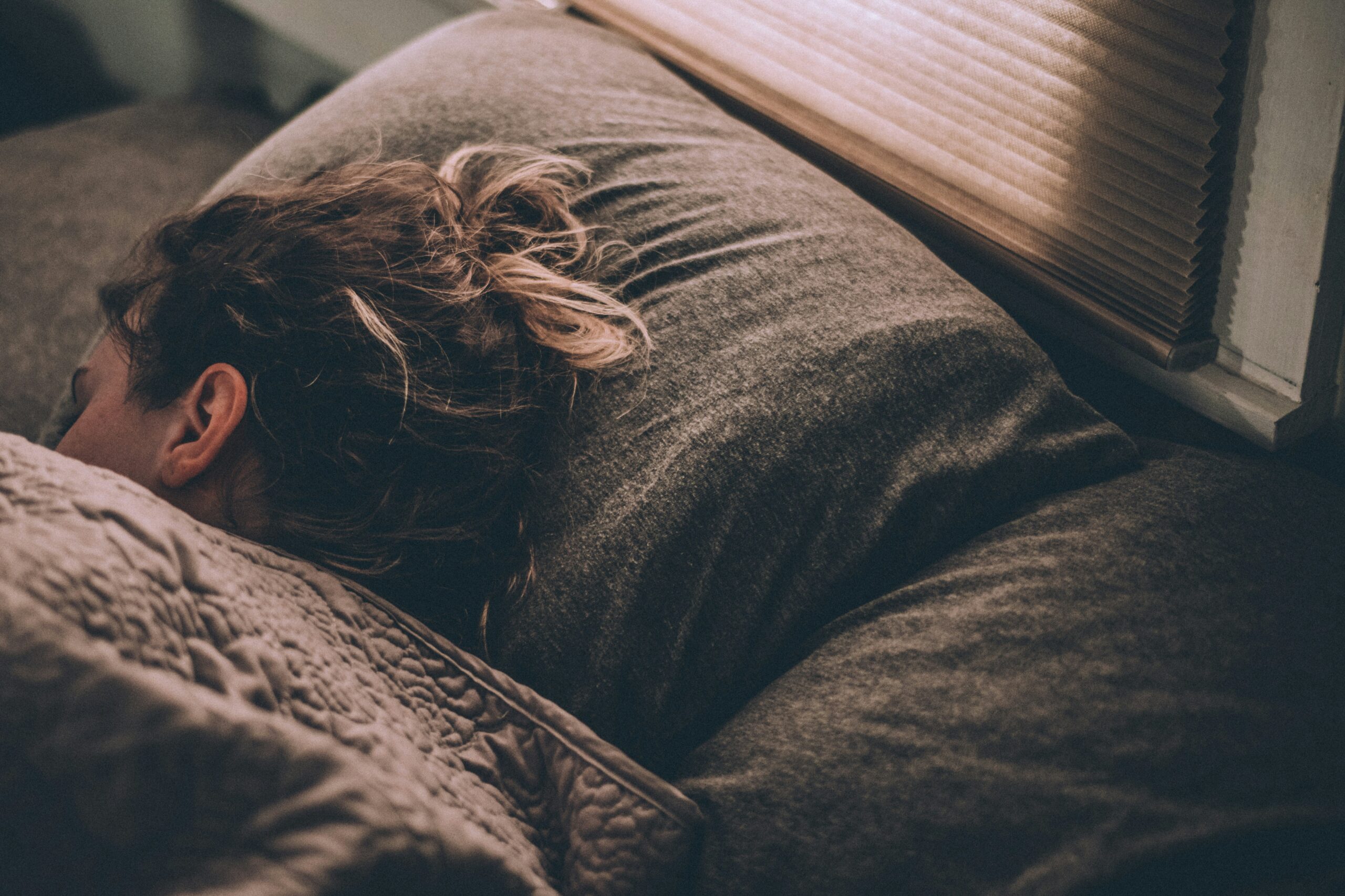 greg-pappas-rUc9hVE-L-E-unsplash the head of someone sleeping in a bed with dark grey sheets