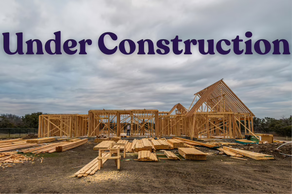 Partially built wood frame of a house with the words "under construction" above it on a grey sky